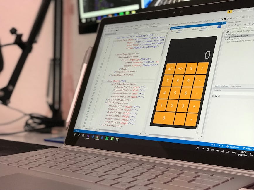 A laptop displaying a programming code editor with lines of HTML and CSS code in various colors on the left side of the screen, and a large digital calculator interface with orange buttons labeled wit